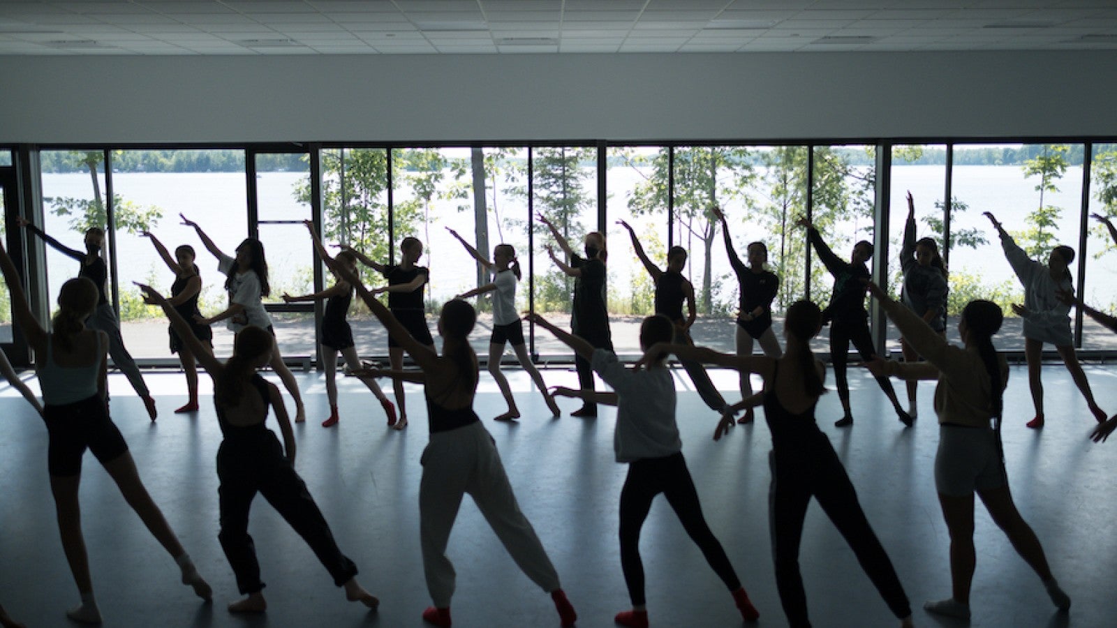 Dance camp students dance in front of lakefront windows