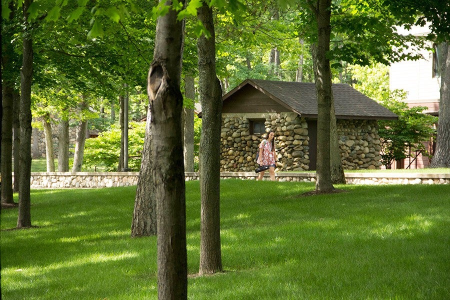 Students walk past a small stone hut