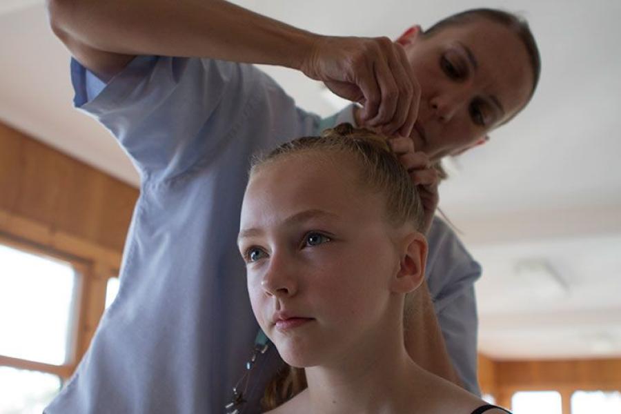 Rachel James helps a junior dance student style her hair for a performance
