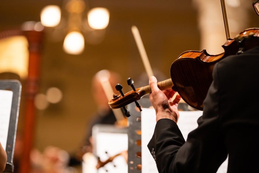 A violinist playing in an orchestra in a concert hall.