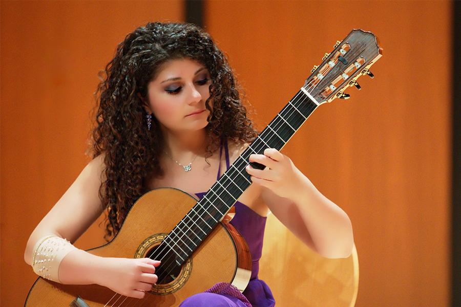 A woman performs on a classical guitar