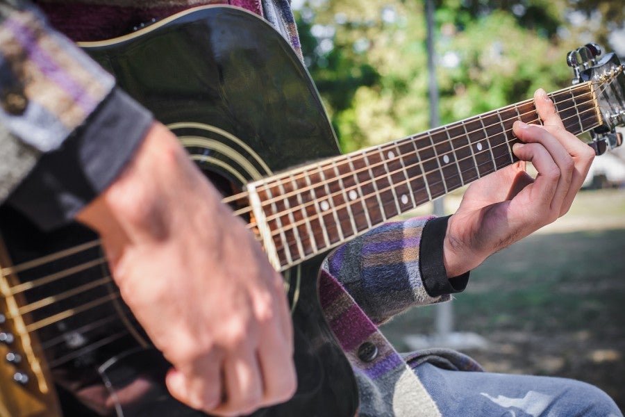 A man is playing an acoustic guitar outside