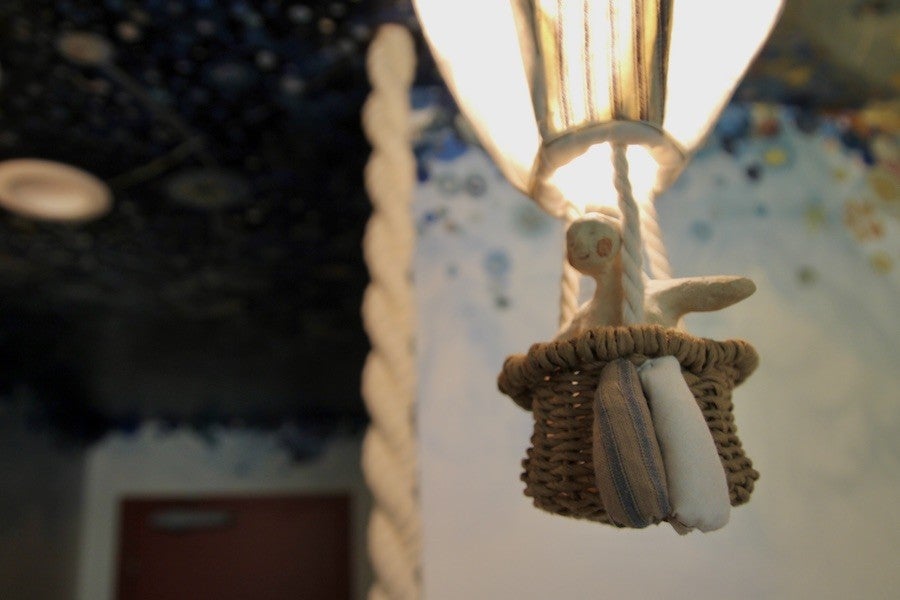 A close-up of a miniature hot air balloon with a human figure riding inside the basket.