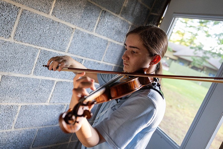 A violinist rehearses in a practice cabin. 