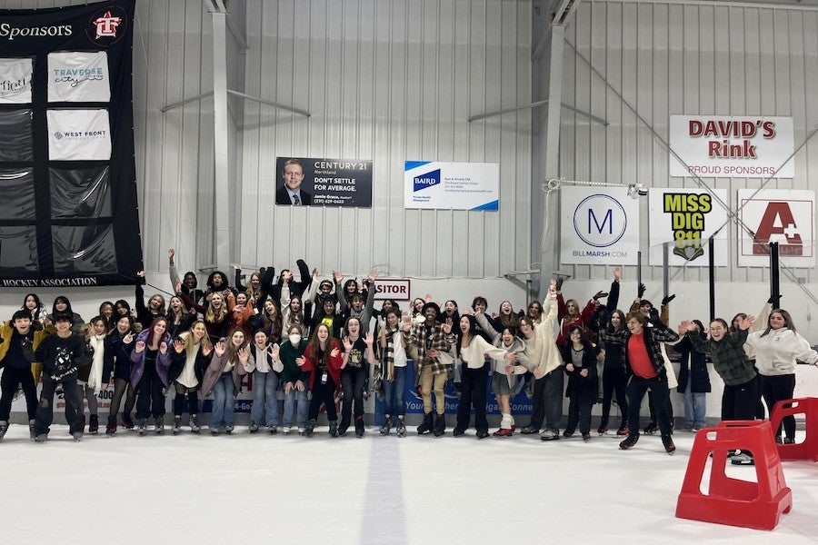 A group of students pose at an ice rink