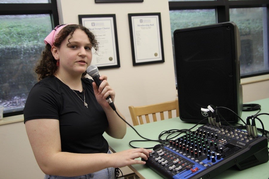 A student works with a microphone and DAW.