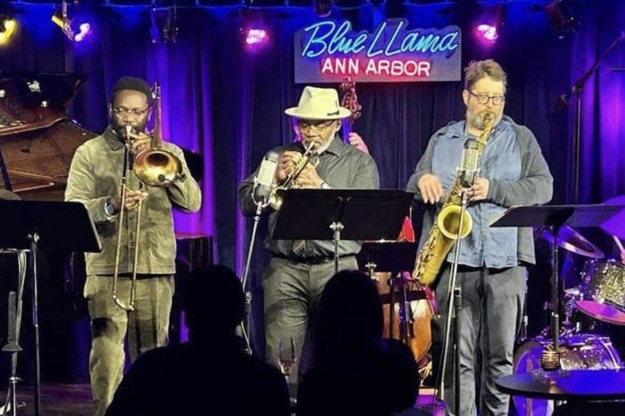 Three musicians perform on a blue-curtained stage at a blues club called Blue Llama.