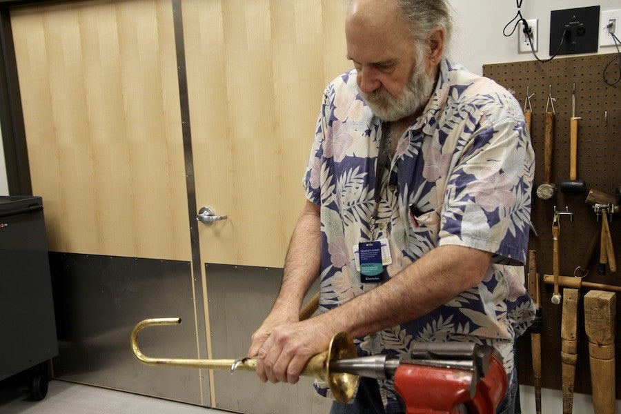 Ken Larson smooths out the dents in a trumpet bell.