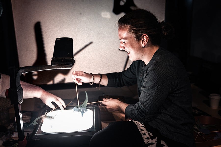 An Interdisciplinary Arts student operates a shadow puppet above an overhead projector.