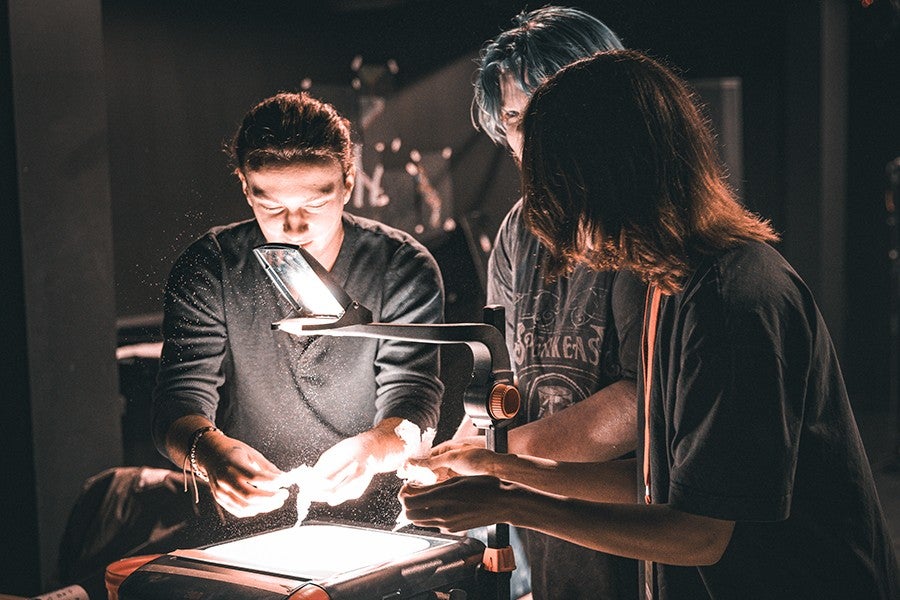 Interdisciplinary Arts students arrange shadow puppets on an overhead projector. 