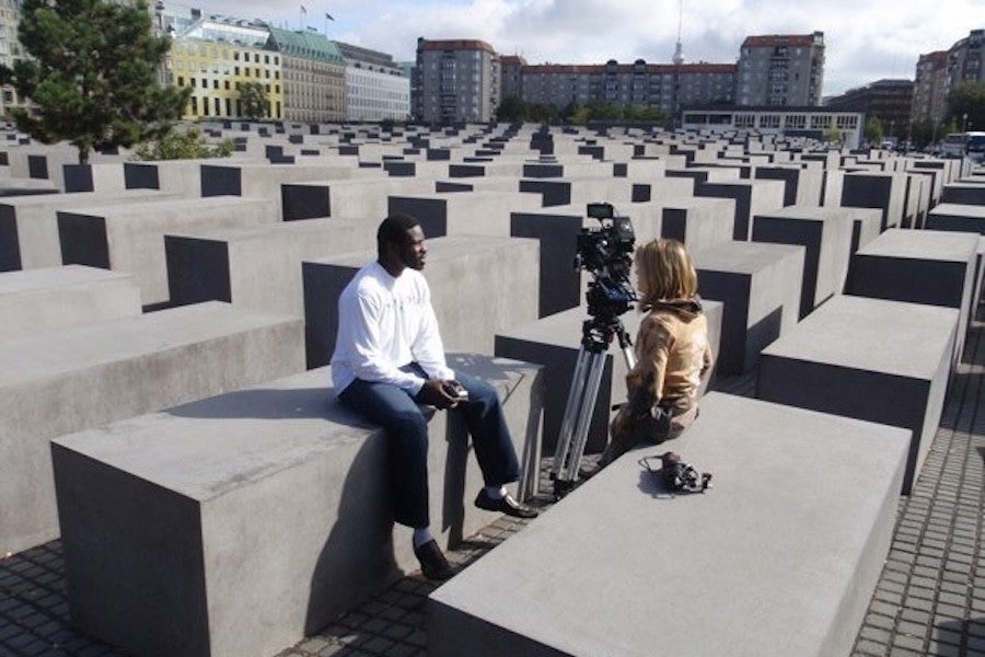 A man and a woman work with a camera at a memorial site. 