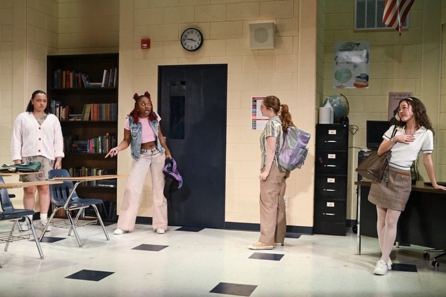 Several students pose dramatically in a classroom.