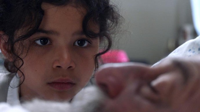 A young girl looks intently at a man's face