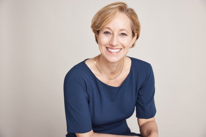 Professional headshot of a blonde woman wearing a navy blue top.