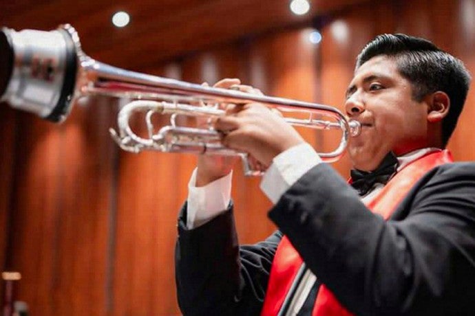 Mauricio Garcia plays the trumpet in a concert hall. 