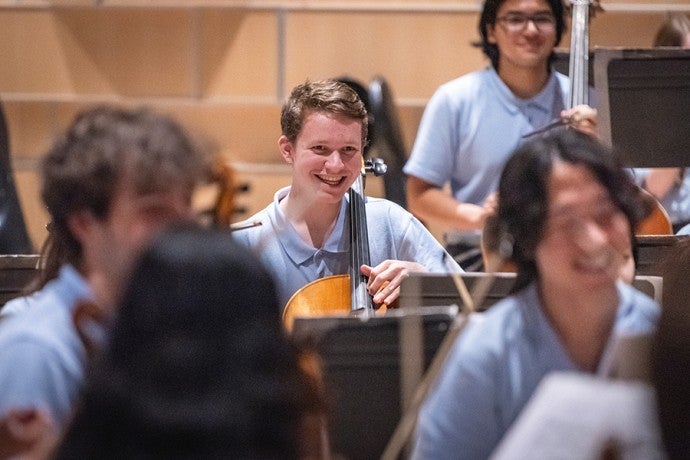 Members of the 2024 Interlochen Philharmonic share a smile during a rehearsal. 