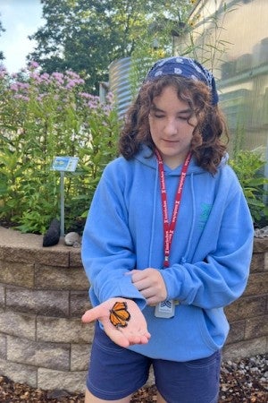 An intermediate Arts Camp student holds a monarch butterfly.