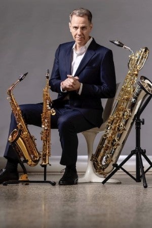 Tim McAllister poses with alto, soprano, and baritone saxophones.