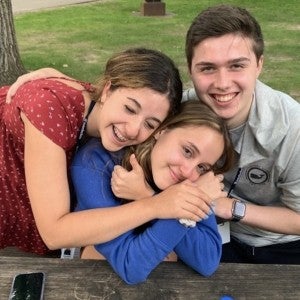 Three students put their arms around each other and smile at the camera.