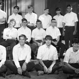 A group of eleven young men and their counselors pose for a photo outside cabin HSB10 