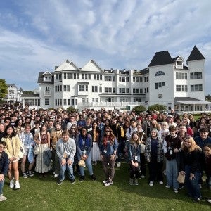 Arts Academy seniors pose in front of a big white resort building on a sunny day.