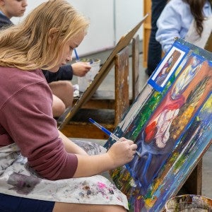 An Interlochen Arts Camp painting student works on canvas. 