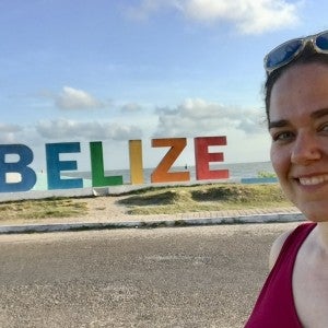 Lauren Hunt in front of a colorful "BELIZE" sign