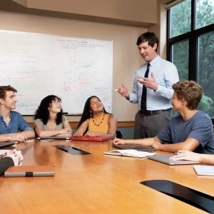 A teacher speaks to a group of seated students. 