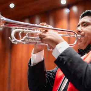 Mauricio Garcia plays the trumpet in a concert hall. 