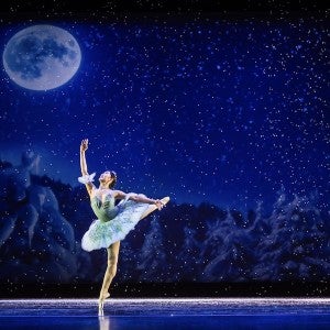 A dancer moves gracefully in front of a wintry scene.