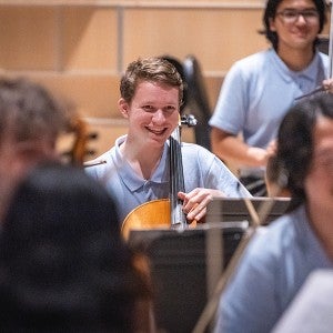 Members of the 2024 Interlochen Philharmonic share a smile during a rehearsal. 