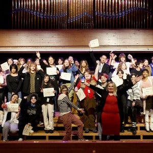 A large group of students and instructors poses expressively for the camera.