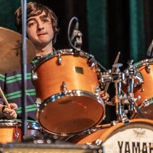 A popular music student plays drums.