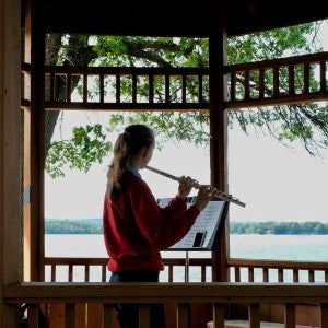 A student practices flute in a gazebo at Interlochen Arts Camp. 