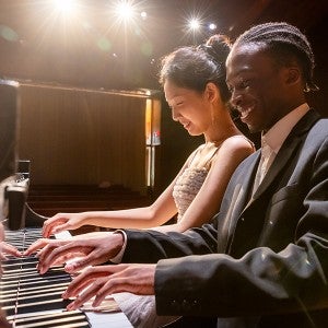 Two students play piano together in Dendrinos Chapel and Recital Hall