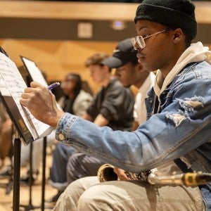 A saxophone student makes notes on sheet music.