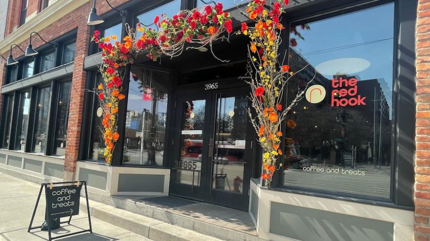 Exterior of The Red Hook café with a floral arrangement above the entrance and a sign advertising "coffee and treats."